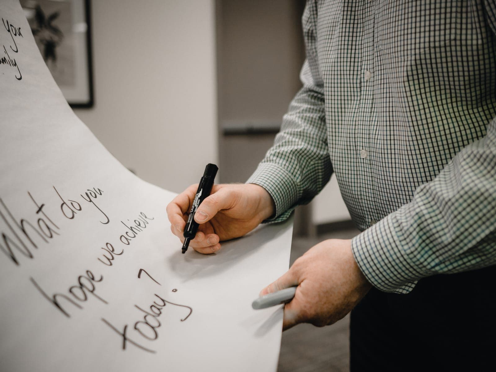 An advisor writing "What do you hope we achieve today?" on a flip chart
